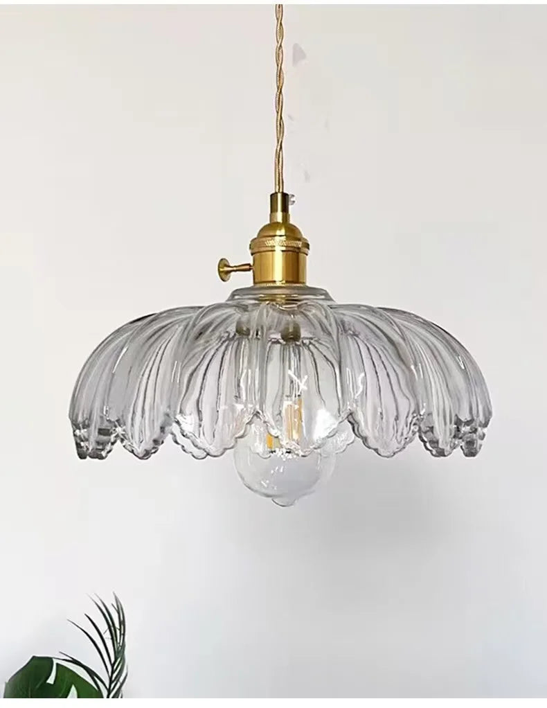 Clear ribbed glass pendant light with a brass socket and hanging cord, shown against a plain light background.