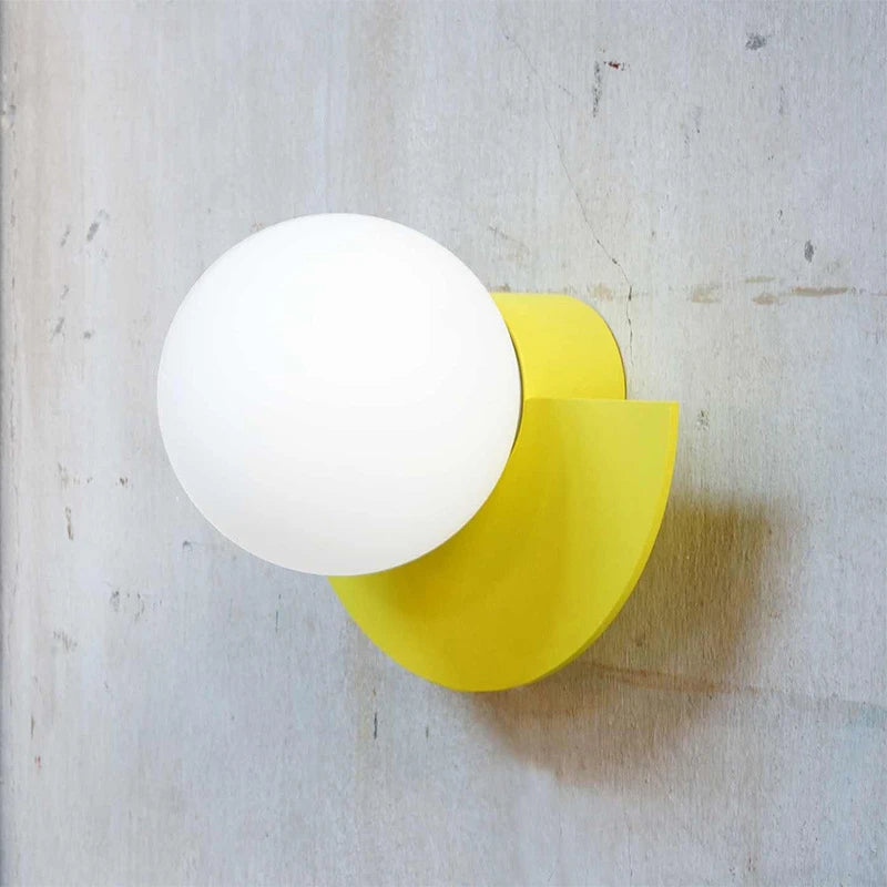White spherical light bulb on a yellow base against a textured white background