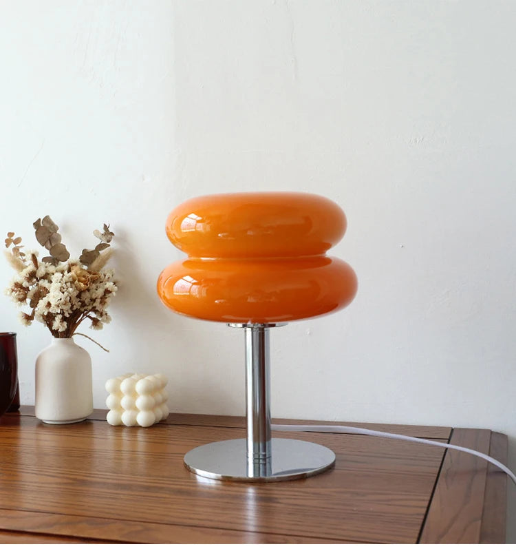 Orange table lamp on a wooden surface with decorative items in the background