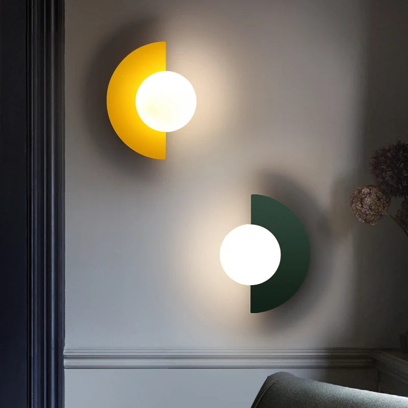 Two modern wall lights, one yellow and one green, on a wall.