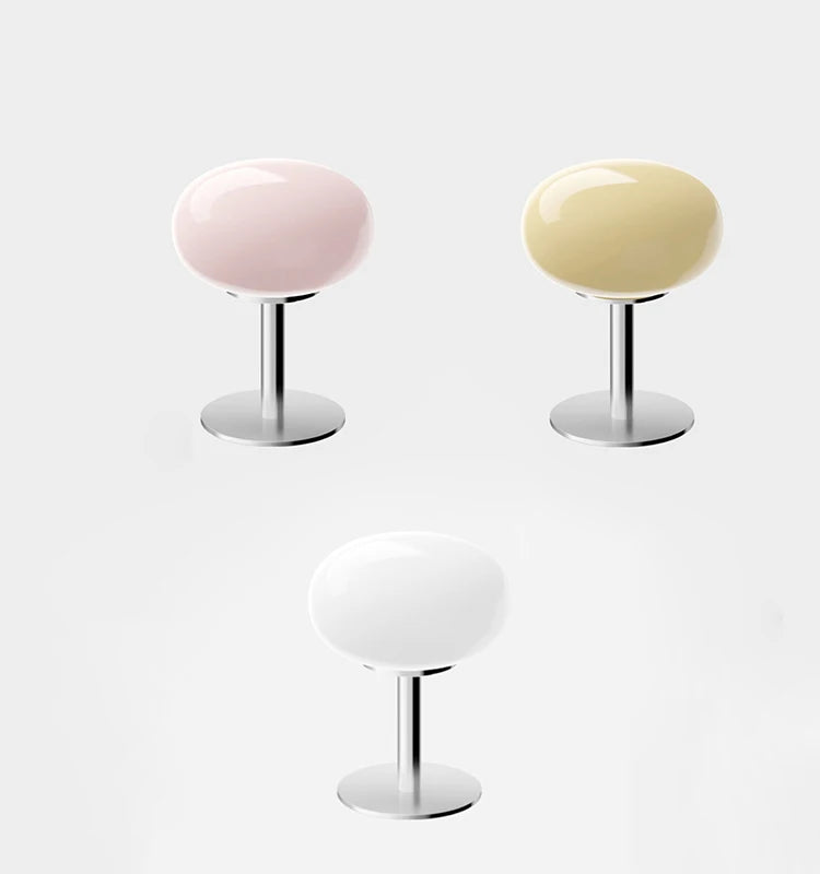 Three egg-shaped stools with pastel-colored tops on a white background