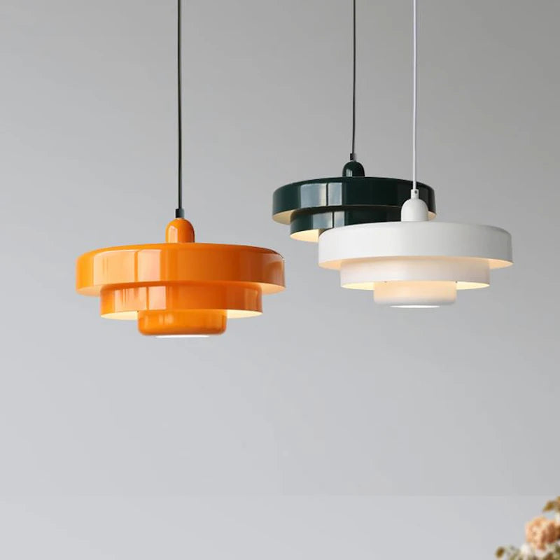 Three pendant lights in orange, black, and white on a gray background