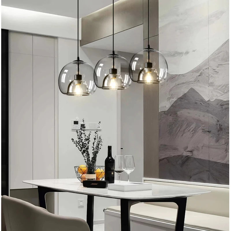 Modern dining room with glass pendant lights, marble table, and decorative elements.