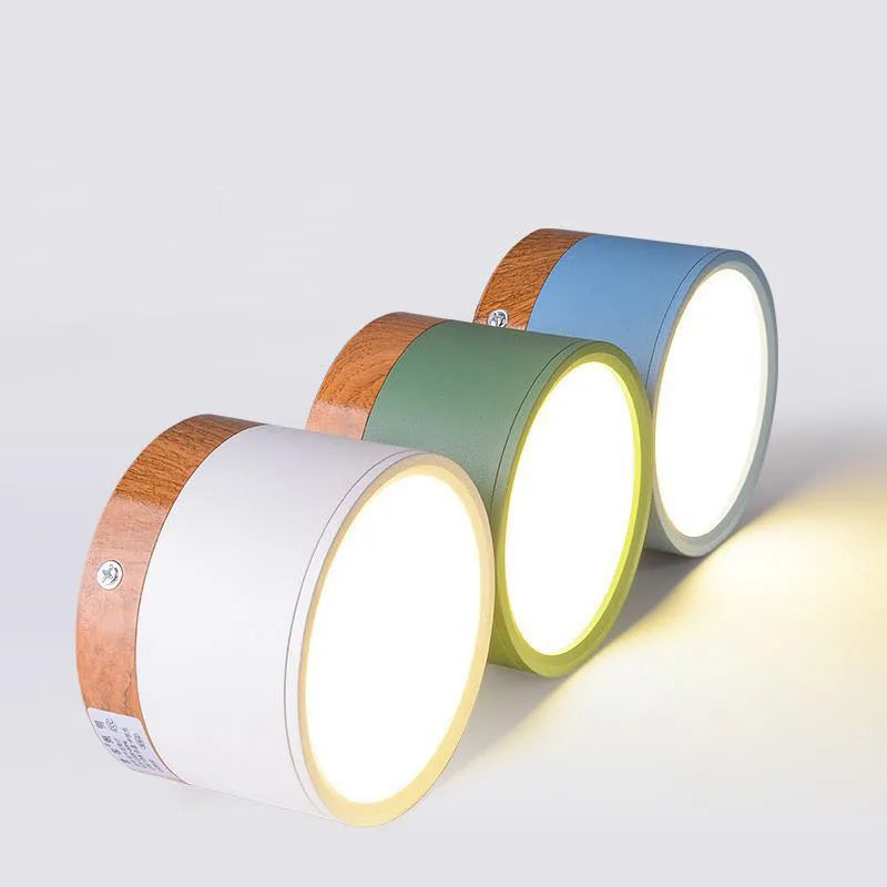 Three cylindrical lamps with wooden and colored accents on a white background