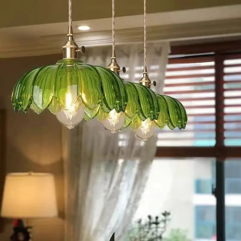 Green glass pendant light fixture in a room with curtains and a lamp.