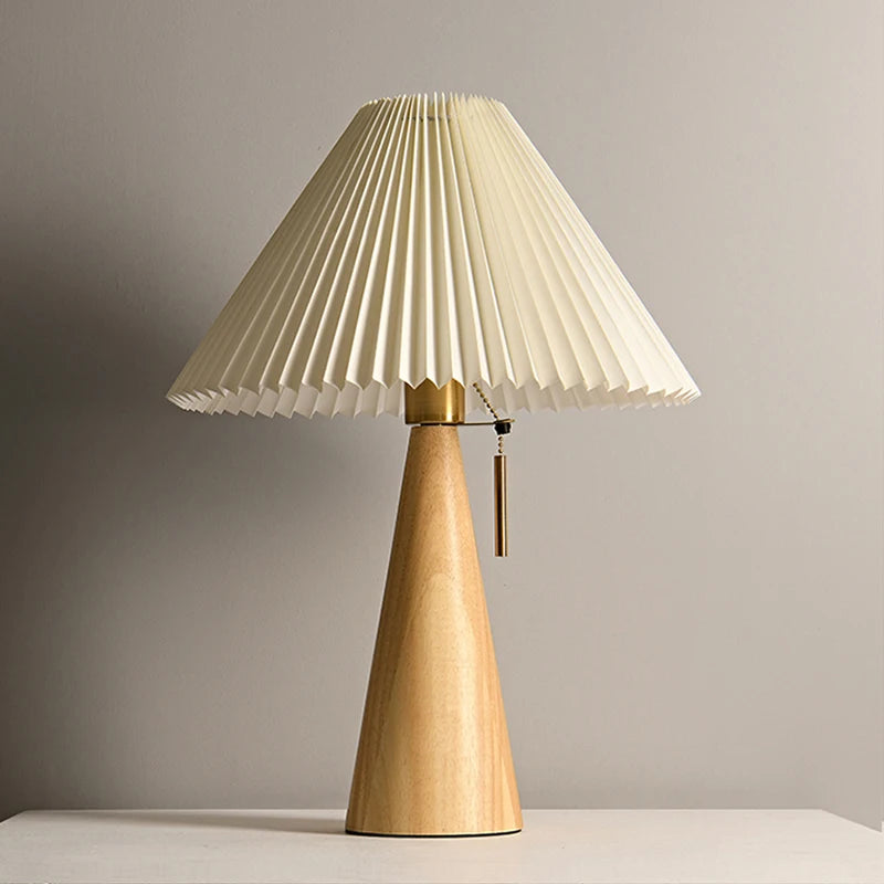 Table lamp with pleated beige shade and wooden base on a neutral background