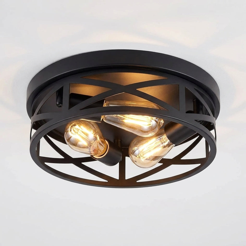 A modern semi-flush mount ceiling light fixture with a matte black metal frame and three glowing warm Edison-style bulbs, shown against a plain white ceiling.